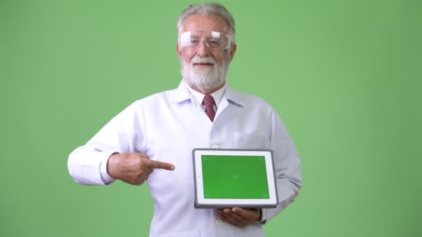 Guapo mayor barbudo médico hombre contra fondo verde — Vídeo de stock