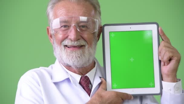 초록색 배경에 대처하기 위해 턱수염을 기르는 노인 의사 — 비디오