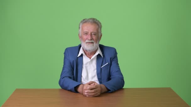 Handsome senior bearded businessman against green background — Stock Video