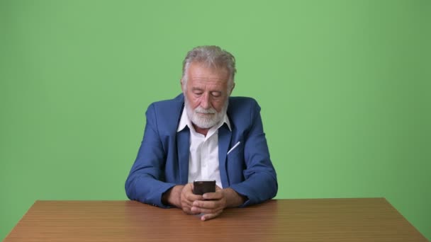 Knappe senior bebaarde zakenman tegen groene achtergrond — Stockvideo