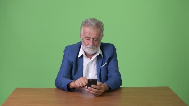 Handsome senior bearded businessman against green background — Stock Video