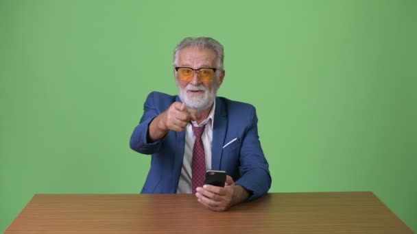 Handsome senior bearded businessman against green background — Stock Video