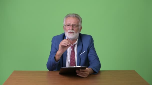 Guapo hombre de negocios barbudo senior contra fondo verde — Vídeos de Stock