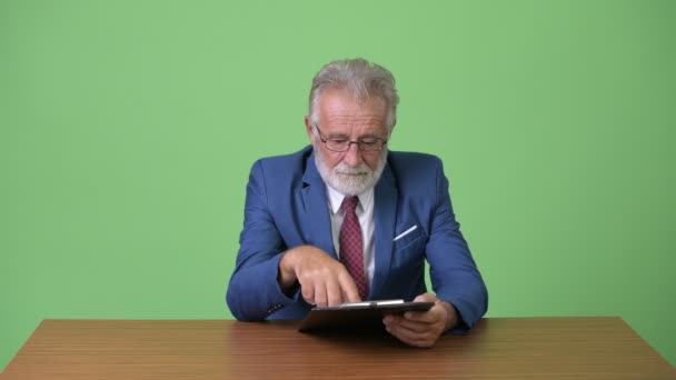 Guapo hombre de negocios barbudo senior contra fondo verde — Vídeos de Stock