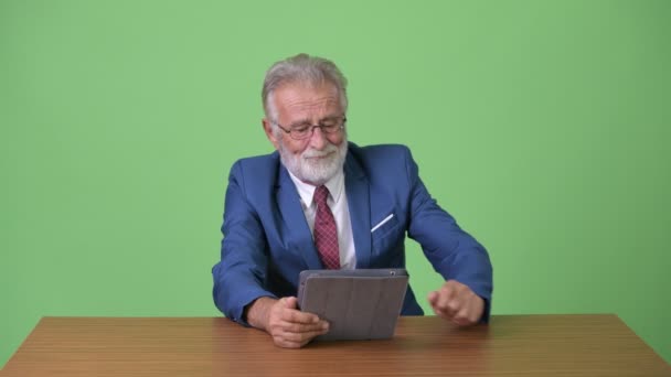 Handsome senior bearded businessman against green background — Stock Video