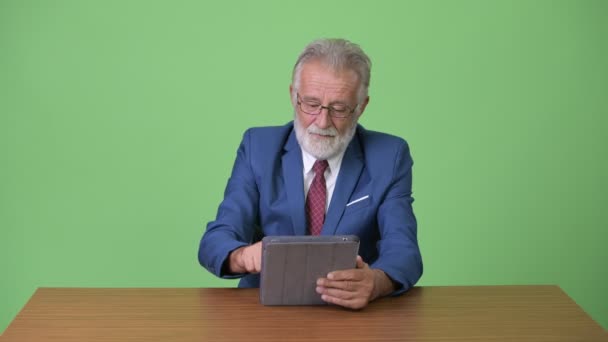 Handsome senior bearded businessman against green background — Stock Video