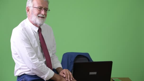 Handsome senior bearded businessman against green background — Stock Video