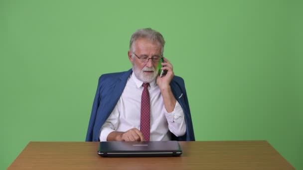 Handsome senior bearded businessman against green background — Stock Video