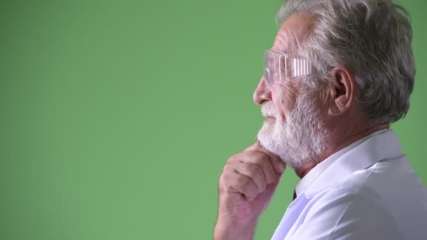 Bonito médico homem barbudo sênior contra fundo verde — Vídeo de Stock