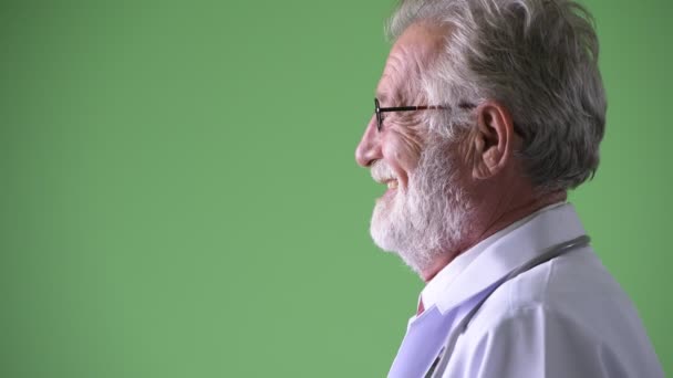 Bonito médico homem barbudo sênior contra fundo verde — Vídeo de Stock