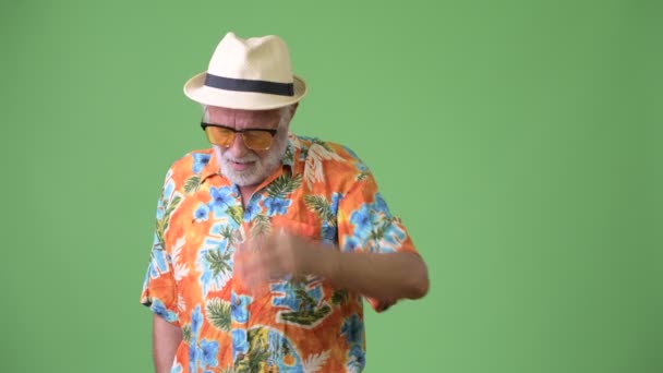 Handsome senior bearded tourist man ready for vacation against green background — Stock Video