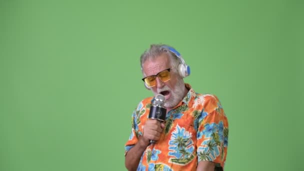 Knappe senior bebaarde toeristische man klaar voor vakantie tegen een groene achtergrond — Stockvideo