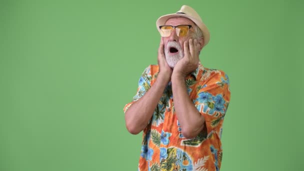 Bonito turista barbudo sênior pronto para férias contra fundo verde — Vídeo de Stock