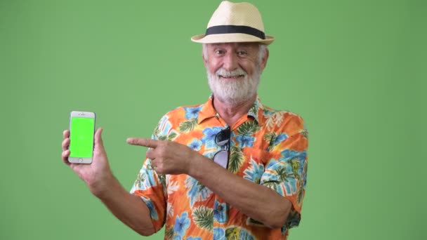 Красивий старший бородатий турист готовий до відпустки на зеленому тлі — стокове відео