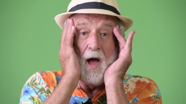 Schöner älterer bärtiger Touristenmann urlaubsreif vor grünem Hintergrund — Stockvideo