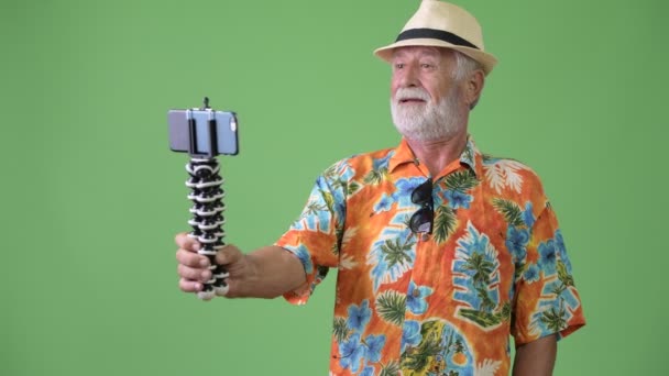 Schöner älterer bärtiger Touristenmann urlaubsreif vor grünem Hintergrund — Stockvideo