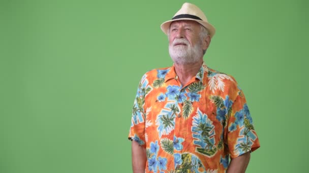 Handsome senior bearded tourist man ready for vacation against green background — Stock Video