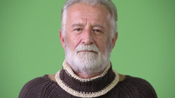 Handsome senior bearded man wearing warm clothing against green background — Stock Video