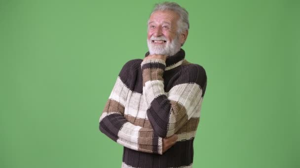 Guapo hombre barbudo mayor con ropa de abrigo sobre fondo verde — Vídeos de Stock
