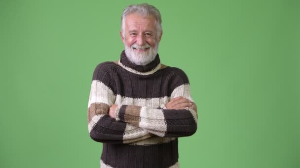 Guapo hombre barbudo mayor con ropa de abrigo sobre fondo verde — Vídeos de Stock