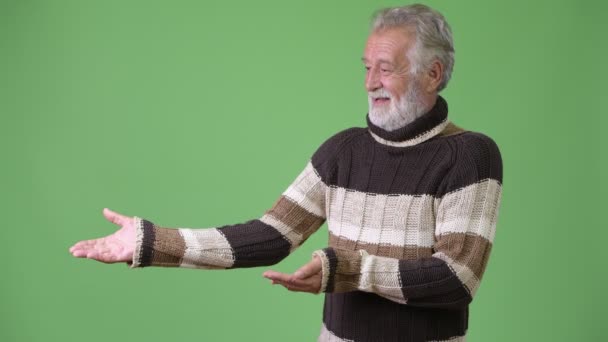 Красивый старший бородатый мужчина в теплой одежде на зеленом фоне — стоковое видео