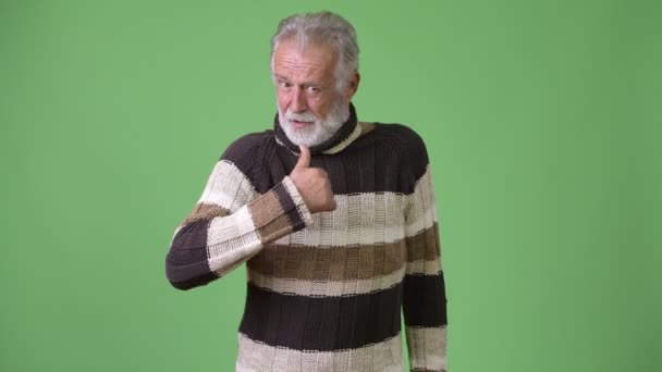 Guapo hombre barbudo mayor con ropa de abrigo sobre fondo verde — Vídeos de Stock