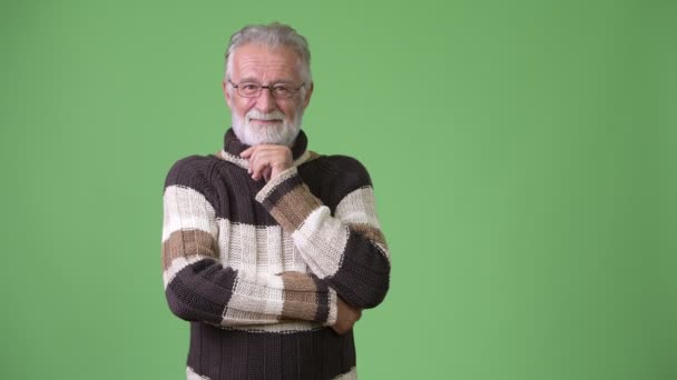 Guapo hombre barbudo mayor con ropa de abrigo sobre fondo verde — Vídeos de Stock