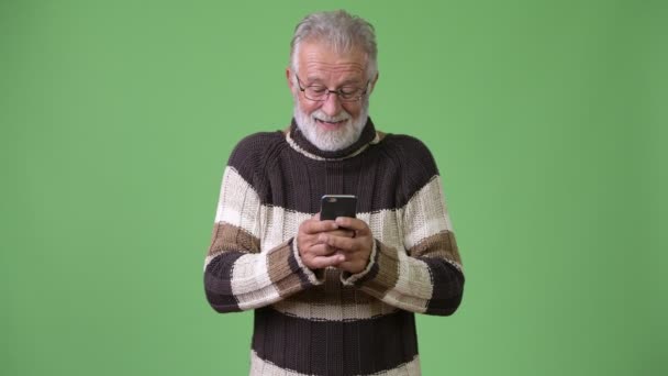 Guapo hombre barbudo mayor con ropa de abrigo sobre fondo verde — Vídeo de stock