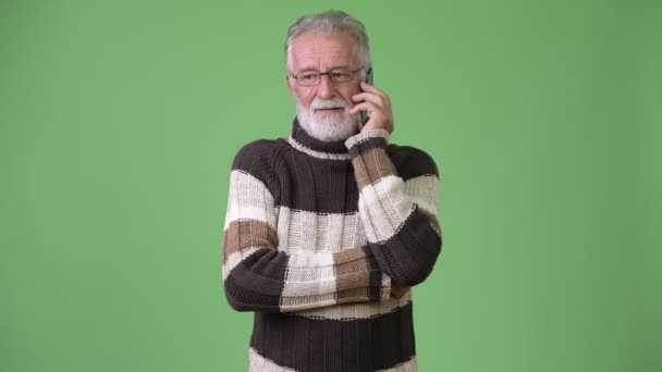 Bonito homem barbudo sênior vestindo roupas quentes contra fundo verde — Vídeo de Stock
