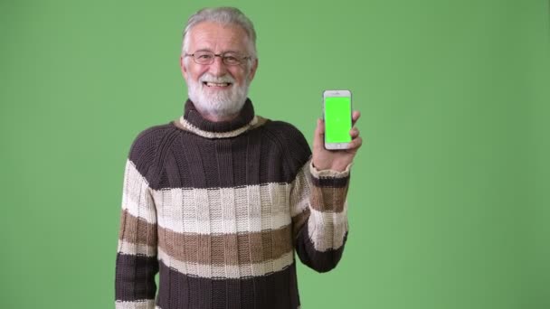 Guapo hombre barbudo mayor con ropa de abrigo sobre fondo verde — Vídeo de stock