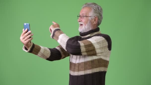 Guapo hombre barbudo mayor con ropa de abrigo sobre fondo verde — Vídeos de Stock