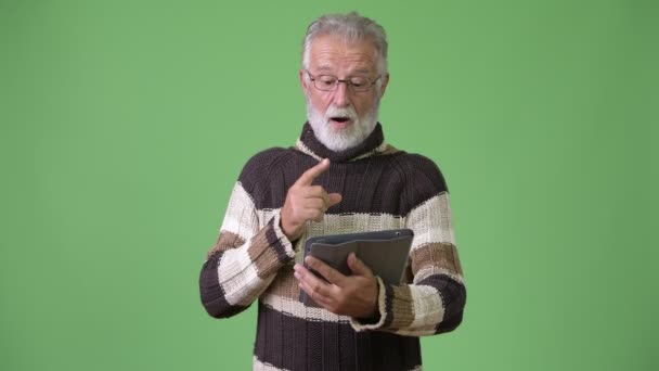 Guapo hombre barbudo mayor con ropa de abrigo sobre fondo verde — Vídeos de Stock