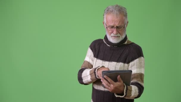 Guapo hombre barbudo mayor con ropa de abrigo sobre fondo verde — Vídeos de Stock