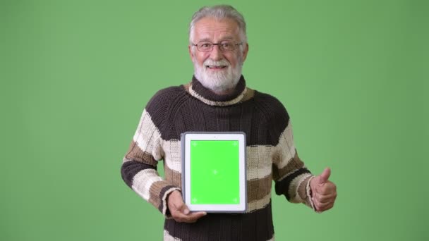 Handsome senior bearded man wearing warm clothing against green background — Stock Video