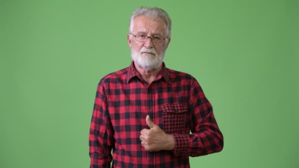 Handsome senior bearded man against green background — Stock Video