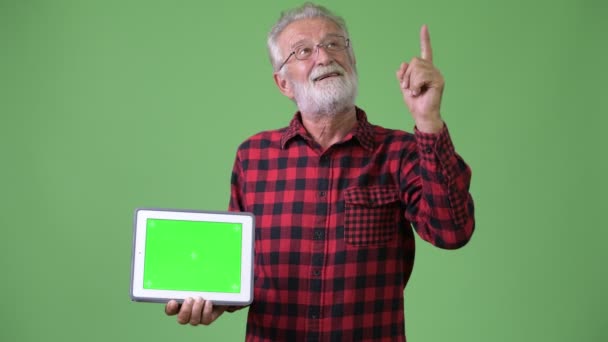 Knappe senior bebaarde man tegen een groene achtergrond — Stockvideo