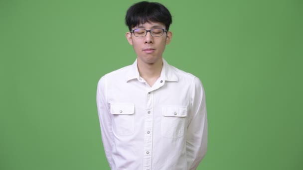 目を閉じてリラックスした若いアジア系のビジネスマン — ストック動画