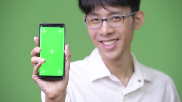 Joven asiático hombre de negocios mostrando teléfono a cámara — Vídeos de Stock