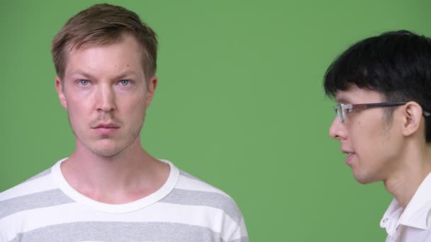 Giovane arrabbiato uomo d'affari asiatico urla al giovane uomo d'affari scandinavo mentre copre le orecchie — Video Stock