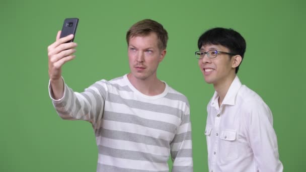 Dos jóvenes y felices empresarios multiétnicos sonriendo mientras se toman selfie juntos — Vídeo de stock