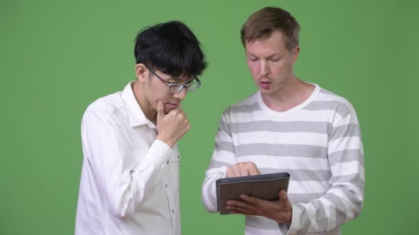 Два молодых многонациональных бизнесмена встречаются с цифровыми планшетами — стоковое видео