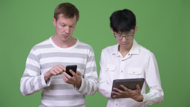 Dois jovens empresários multi-étnicos usando telefone e tablet digital para o conceito de mídia social — Vídeo de Stock