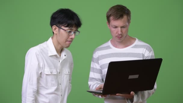 Two sad young multi-ethnic businessmen using laptop while getting bad news together — Stock Video