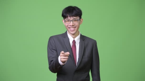 카메라를 가리키는 동안 웃 고 젊은 행복 아시아 사업가 — 비디오