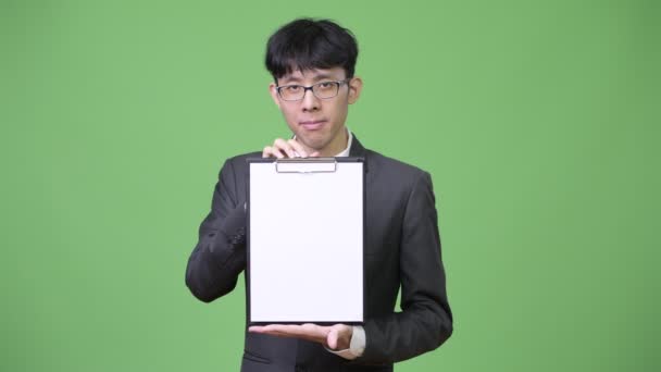 Young Asian businessman showing clipboard to camera — Stock Video