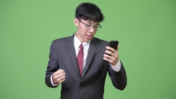 Young sad Asian businessman using phone and getting bad news — Stock Video