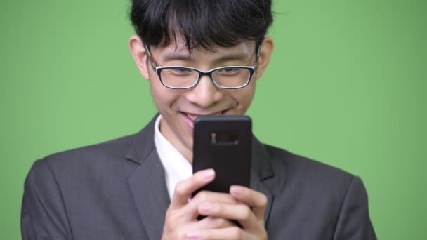 Jeune homme d'affaires asiatique heureux souriant tout en utilisant le téléphone — Video