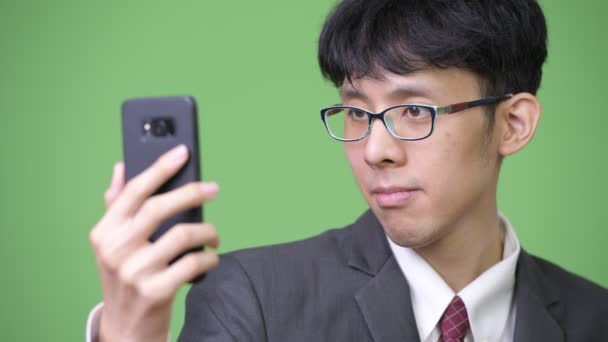 Молодой азиатский бизнесмен с помощью телефона и сенсорного экрана — стоковое видео