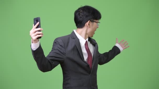 Joven feliz asiático empresario sonriendo mientras videollamada en el teléfono — Vídeos de Stock