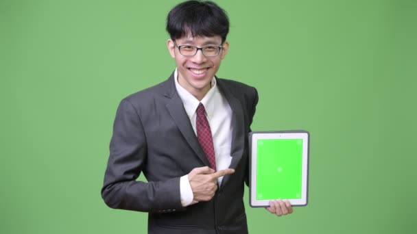 Genç mutlu Asya işadamı gösteren dijital tablet kamera ve işaret parmağı — Stok video